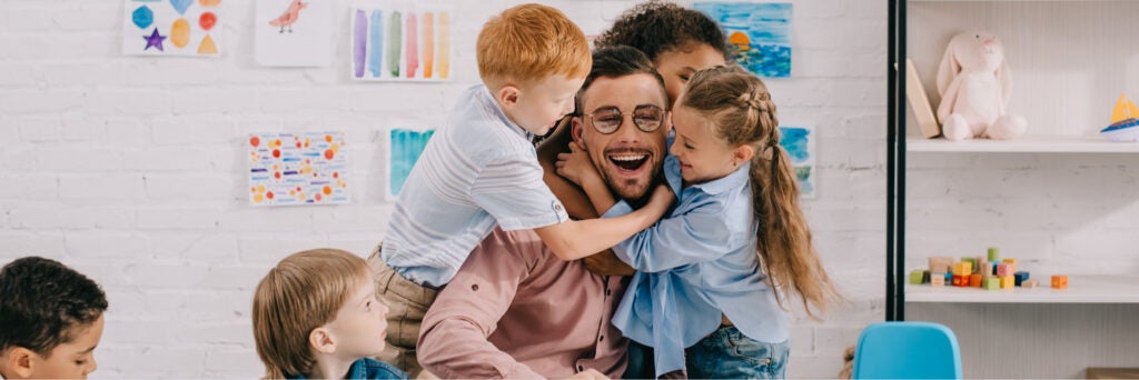 decorative image of teacher playing with children at the classroom